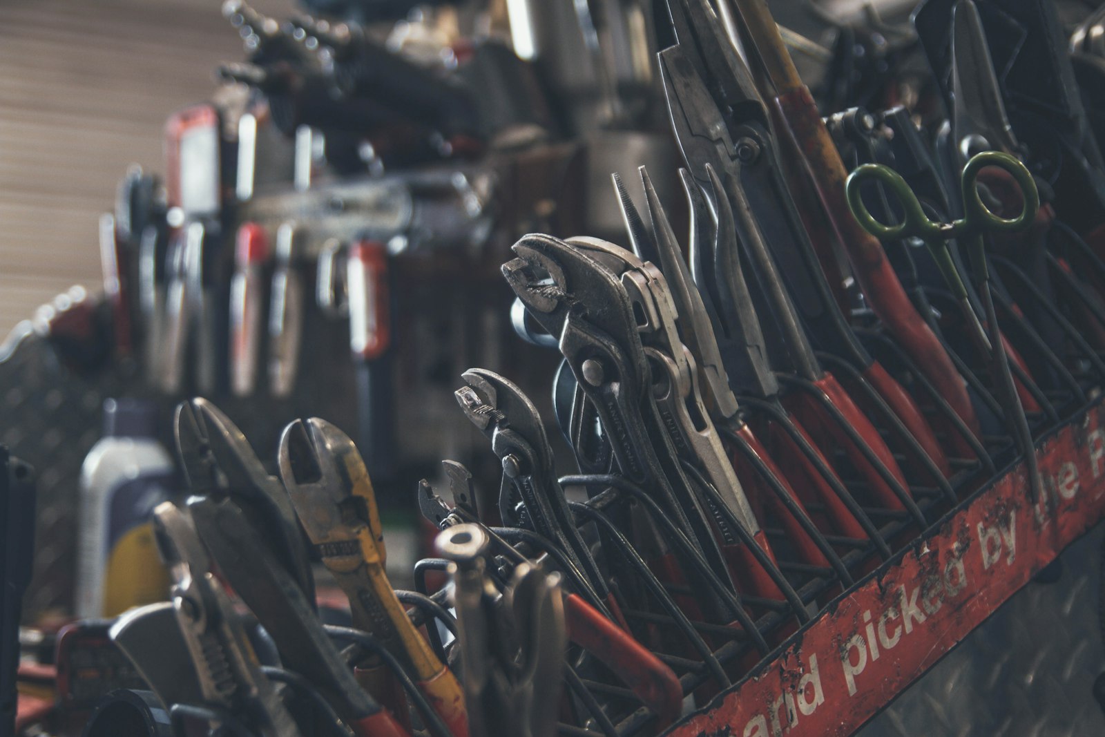 A rack of pliers and hand tools in a workshop.